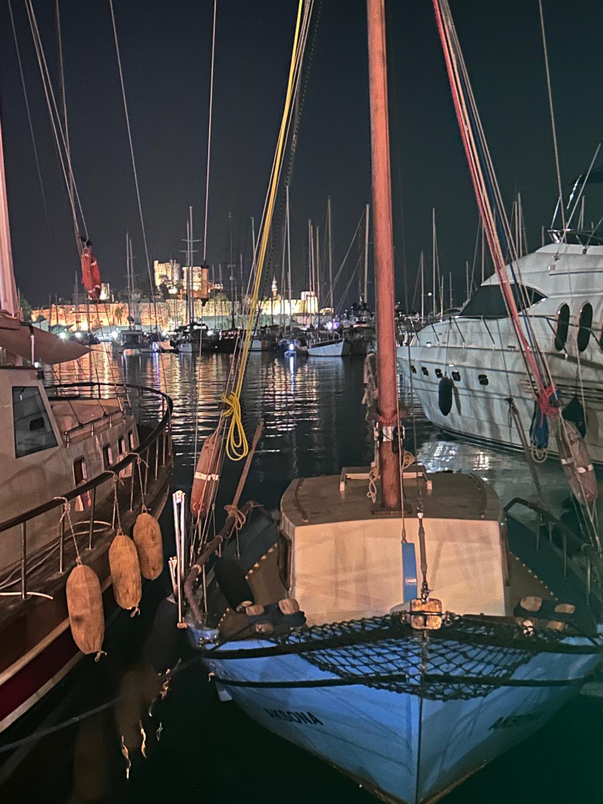Gece teknelerin arasından görülen aydınlatılmış Bodrum Kalesi