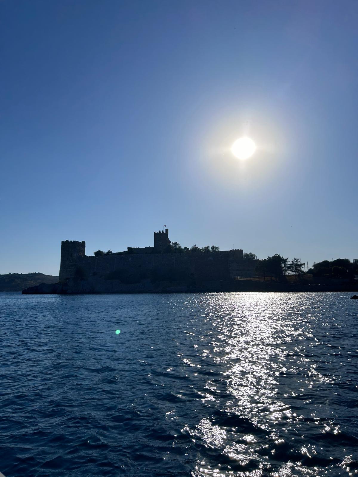 Parlak güneş ve deniz üzerinde siluet hâlinde Bodrum Kalesi